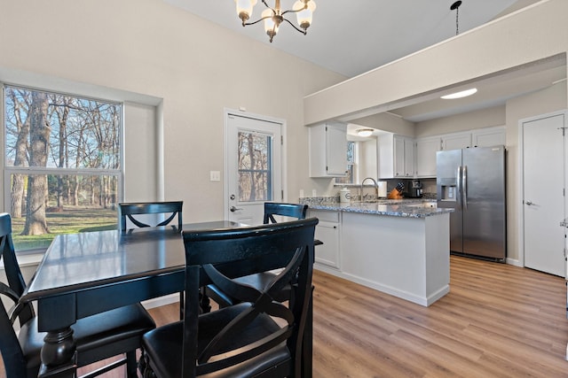 dining room with an inviting chandelier, sink, and light hardwood / wood-style floors