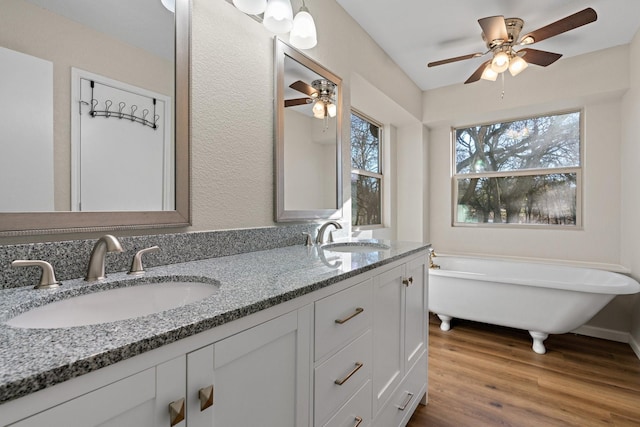 bathroom featuring wood-type flooring, a bath, vanity, and ceiling fan