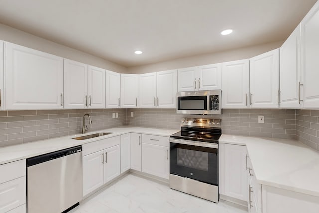 kitchen with a sink, tasteful backsplash, marble finish floor, and appliances with stainless steel finishes