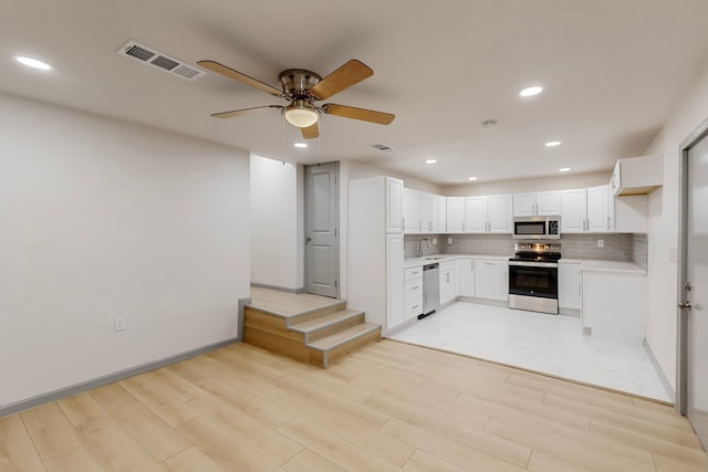 kitchen with visible vents, stainless steel appliances, light wood-style floors, light countertops, and decorative backsplash