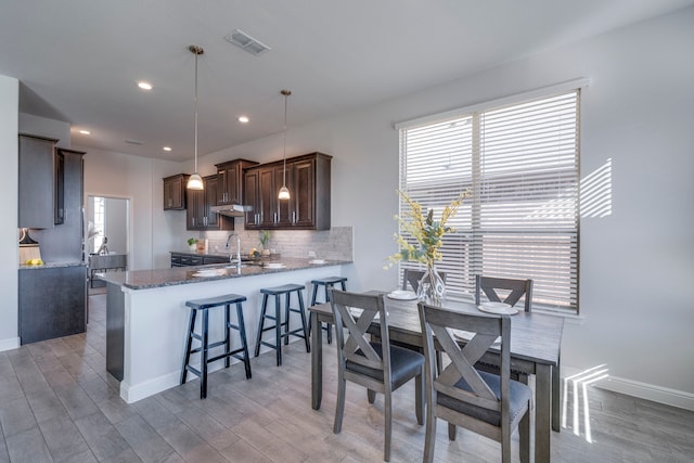 kitchen featuring kitchen peninsula, sink, hanging light fixtures, and light wood-type flooring