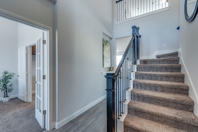 stairs with hardwood / wood-style flooring and a high ceiling