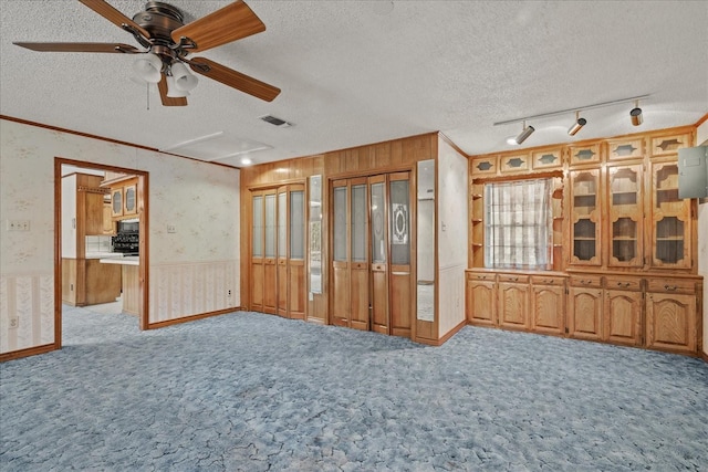 unfurnished living room with ceiling fan, ornamental molding, light colored carpet, and a textured ceiling