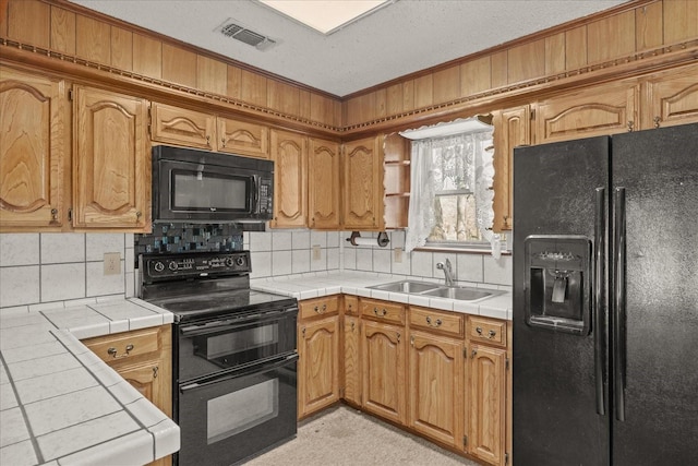 kitchen featuring sink, tile countertops, backsplash, and black appliances