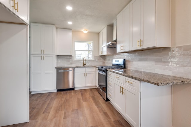 kitchen with sink, white cabinetry, stainless steel appliances, light hardwood / wood-style floors, and stone countertops