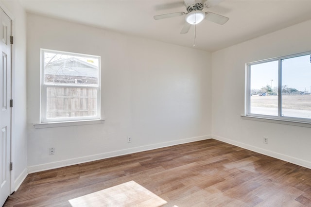 unfurnished room featuring ceiling fan, a wealth of natural light, and light wood-type flooring