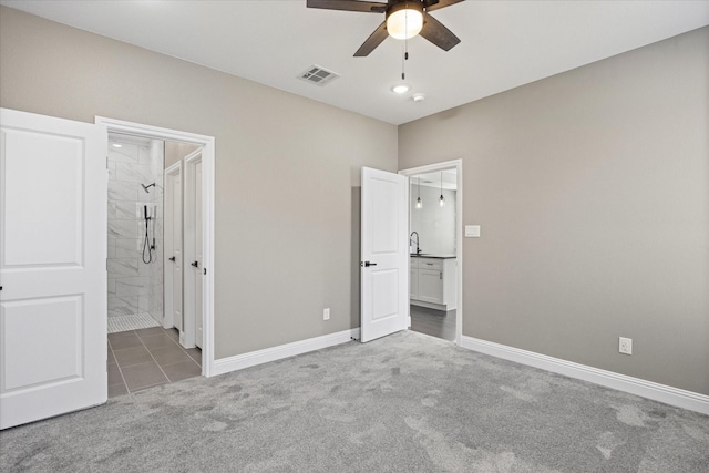 unfurnished bedroom featuring ceiling fan, ensuite bathroom, sink, and dark colored carpet