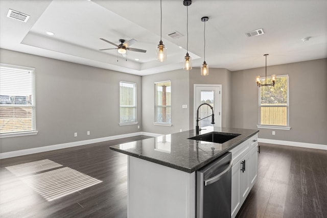 kitchen with white cabinetry, sink, a tray ceiling, and a center island with sink