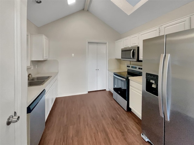 kitchen with appliances with stainless steel finishes, beamed ceiling, white cabinetry, sink, and dark wood-type flooring