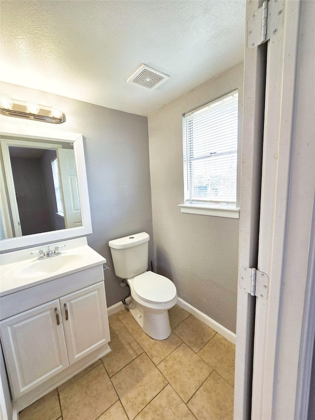 bathroom featuring tile patterned flooring, vanity, a textured ceiling, and toilet