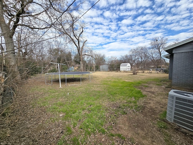 view of yard with a trampoline, central AC unit, and a storage unit