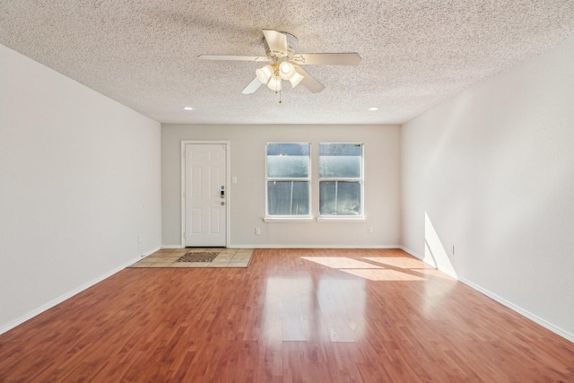 unfurnished room with ceiling fan, a textured ceiling, and light wood-type flooring