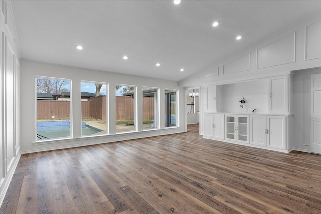 unfurnished living room with lofted ceiling, dark wood-type flooring, and an inviting chandelier