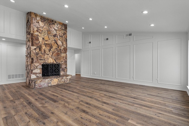 unfurnished living room featuring lofted ceiling, a stone fireplace, and dark wood-type flooring