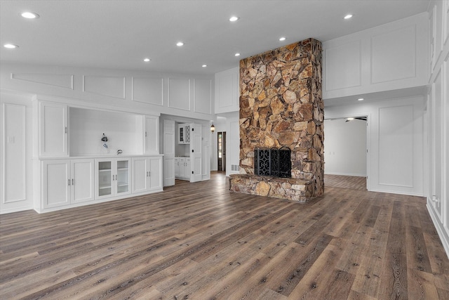 unfurnished living room featuring lofted ceiling, a stone fireplace, and dark hardwood / wood-style floors