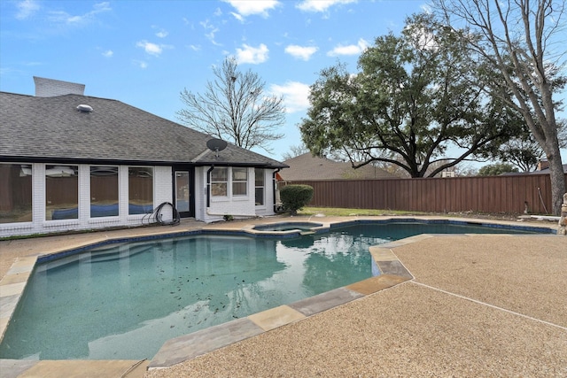 view of swimming pool featuring a patio area, a pool with connected hot tub, fence, and a diving board