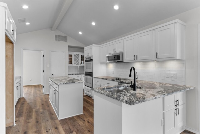 kitchen featuring white cabinetry, stainless steel appliances, and dark stone counters