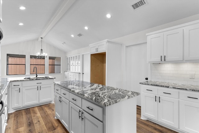 kitchen with visible vents, dark wood finished floors, lofted ceiling with beams, a kitchen island, and a sink