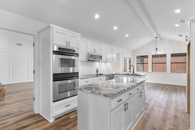 kitchen with appliances with stainless steel finishes, white cabinetry, vaulted ceiling with beams, sink, and kitchen peninsula