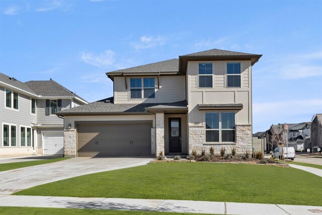 prairie-style house with a garage, a shingled roof, concrete driveway, stone siding, and a front yard