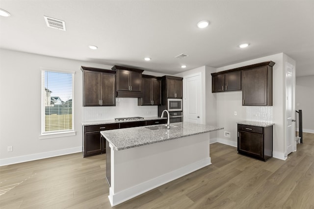 kitchen with visible vents, appliances with stainless steel finishes, a sink, dark brown cabinets, and light wood-type flooring