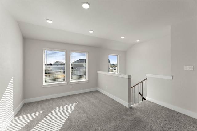 carpeted empty room featuring lofted ceiling, baseboards, and recessed lighting