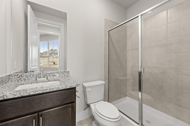 bathroom with a stall shower, vanity, toilet, and baseboards