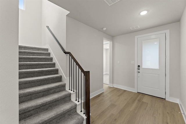 entryway featuring stairs, wood finished floors, visible vents, and baseboards