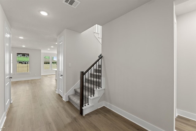 stairway with recessed lighting, visible vents, baseboards, and wood finished floors