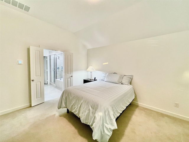 bedroom with light carpet, connected bathroom, and vaulted ceiling