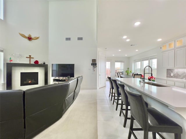 living area featuring visible vents, a lit fireplace, and light tile patterned flooring