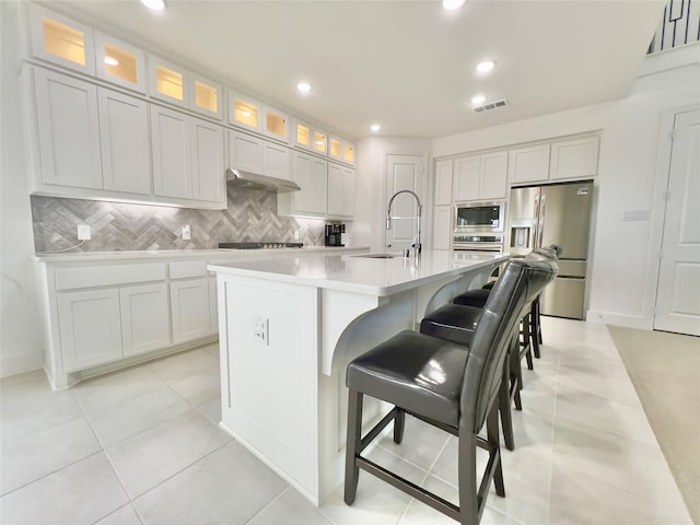 kitchen with tasteful backsplash, visible vents, an island with sink, appliances with stainless steel finishes, and a sink