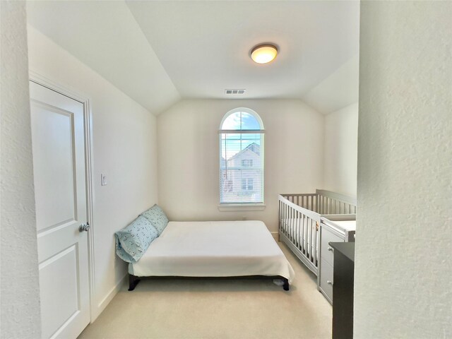 bedroom featuring light carpet, visible vents, baseboards, and lofted ceiling