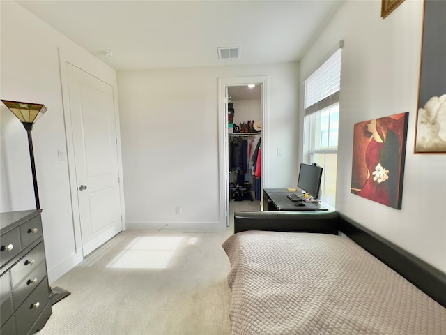 carpeted bedroom featuring a walk in closet and a closet