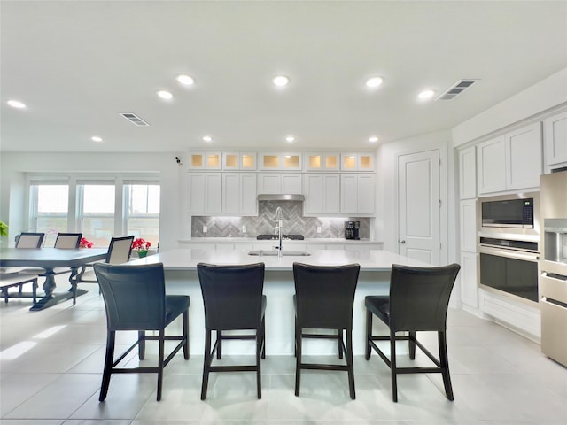 kitchen with white cabinetry, stainless steel appliances, a large island, and tasteful backsplash