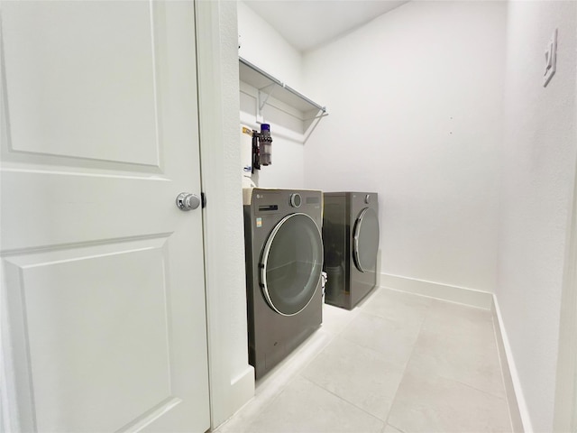 clothes washing area with light tile patterned floors and washer and dryer