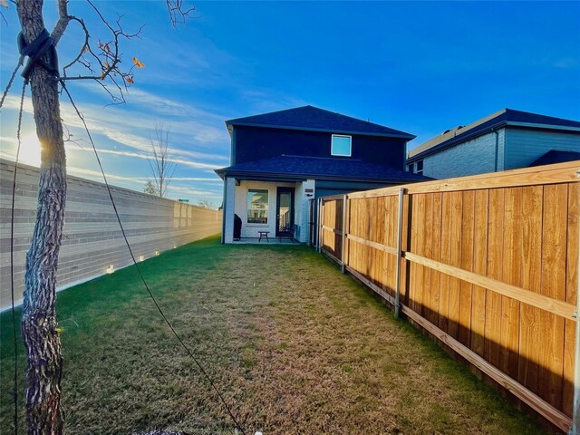 rear view of property with a lawn, a fenced backyard, and roof with shingles