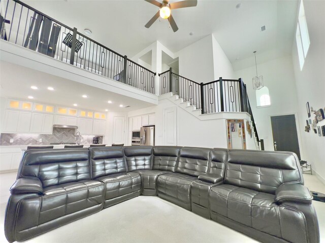 living area with stairway, visible vents, a ceiling fan, and a towering ceiling