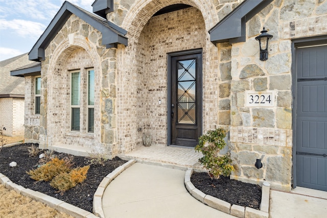 view of exterior entry with stone siding and brick siding