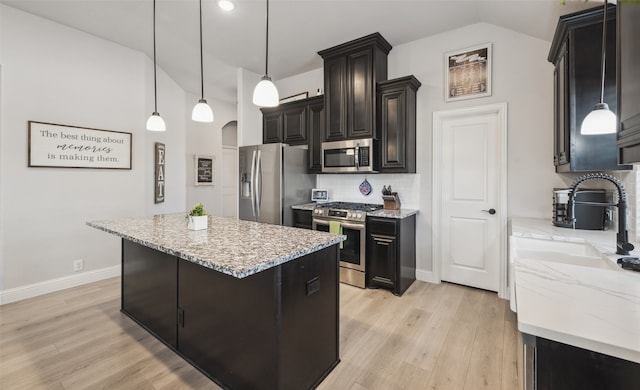 kitchen with tasteful backsplash, lofted ceiling, light wood-style flooring, light stone countertops, and stainless steel appliances