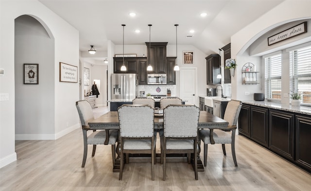 dining area featuring baseboards, arched walkways, vaulted ceiling, light wood-style floors, and recessed lighting