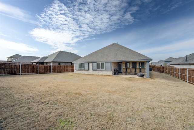 rear view of house with a fenced backyard, a shingled roof, brick siding, a yard, and a patio area