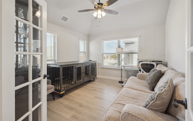 living area with vaulted ceiling, plenty of natural light, wood finished floors, and visible vents