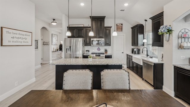 kitchen featuring a center island, stainless steel appliances, tasteful backsplash, visible vents, and a sink