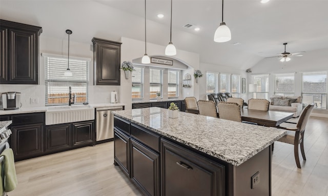 kitchen featuring lofted ceiling, a kitchen island, backsplash, stainless steel dishwasher, and a sink