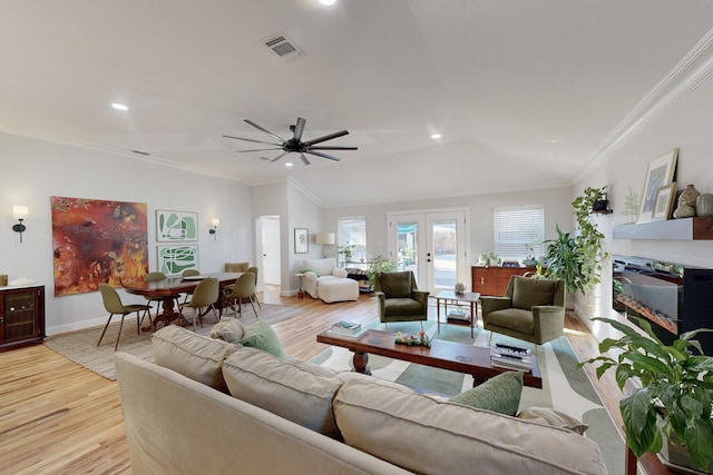 living room with lofted ceiling, ceiling fan, crown molding, light wood-type flooring, and french doors