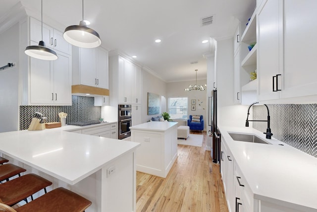 kitchen with a kitchen island, white cabinetry, backsplash, a kitchen bar, and hanging light fixtures