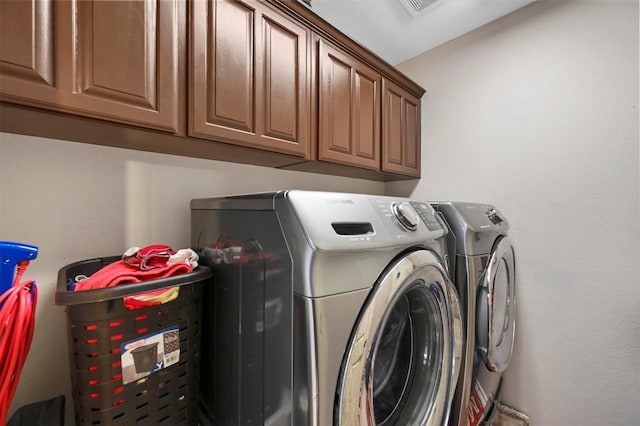 clothes washing area featuring cabinets and washing machine and clothes dryer