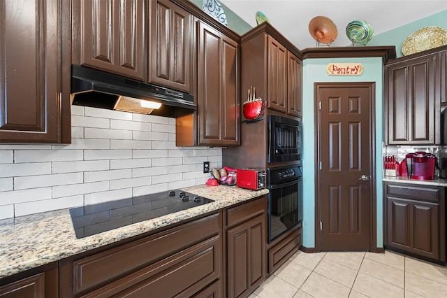 kitchen featuring backsplash, light tile patterned floors, light stone counters, and black appliances