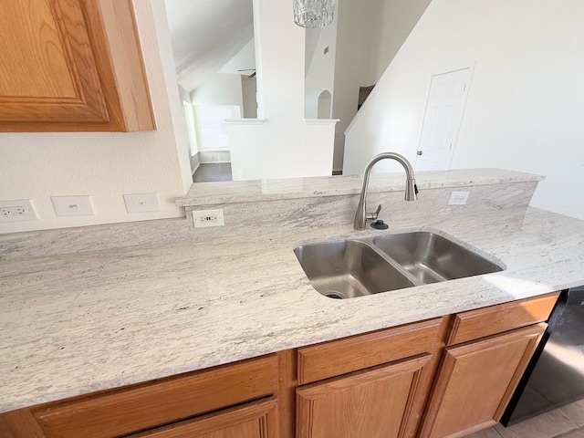 kitchen with light stone countertops, sink, lofted ceiling, and kitchen peninsula